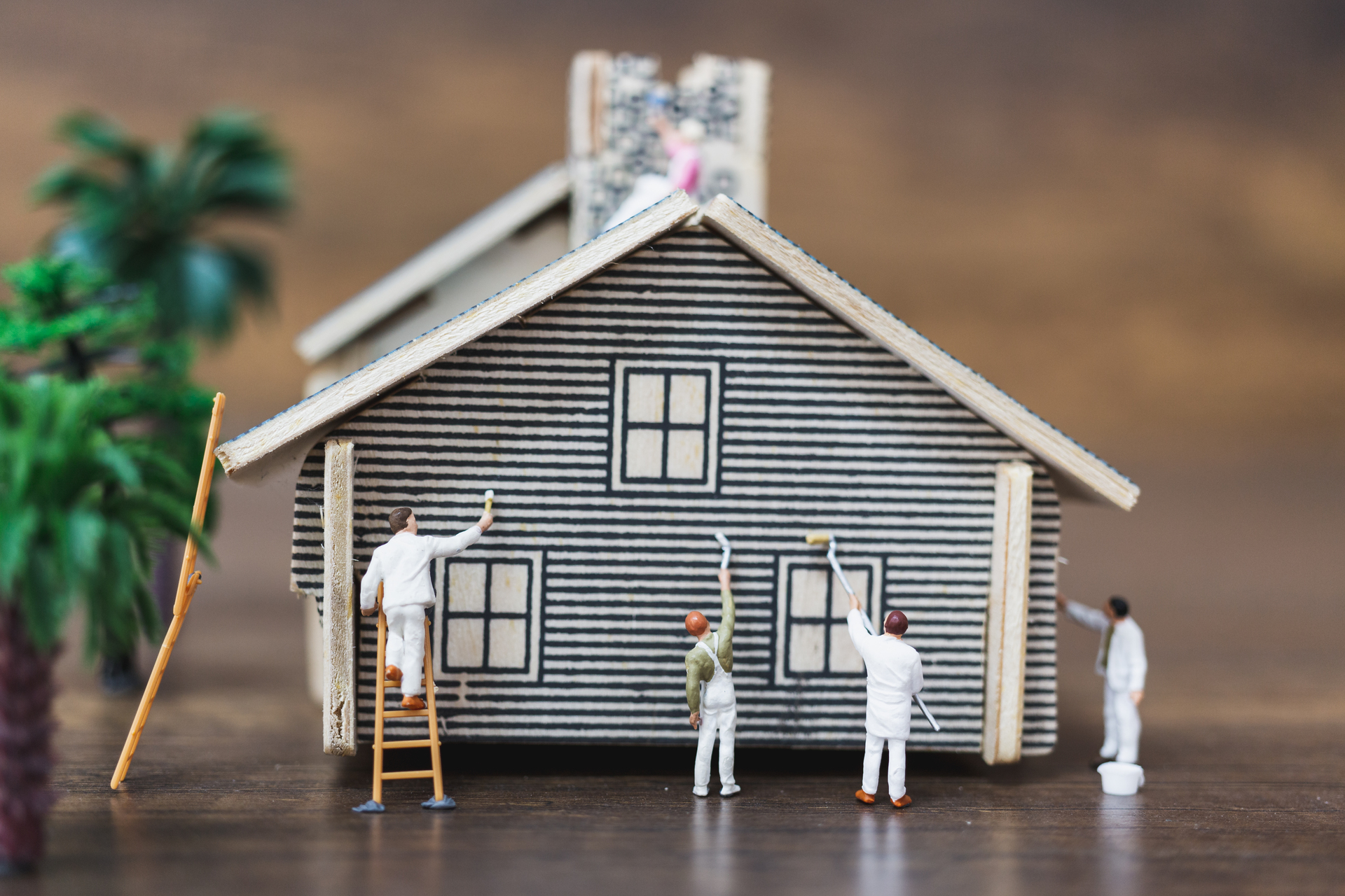 Miniaturowi ludzie: Zespół pracowników maluje nowy dom. Koncepcja metamorfozy domu