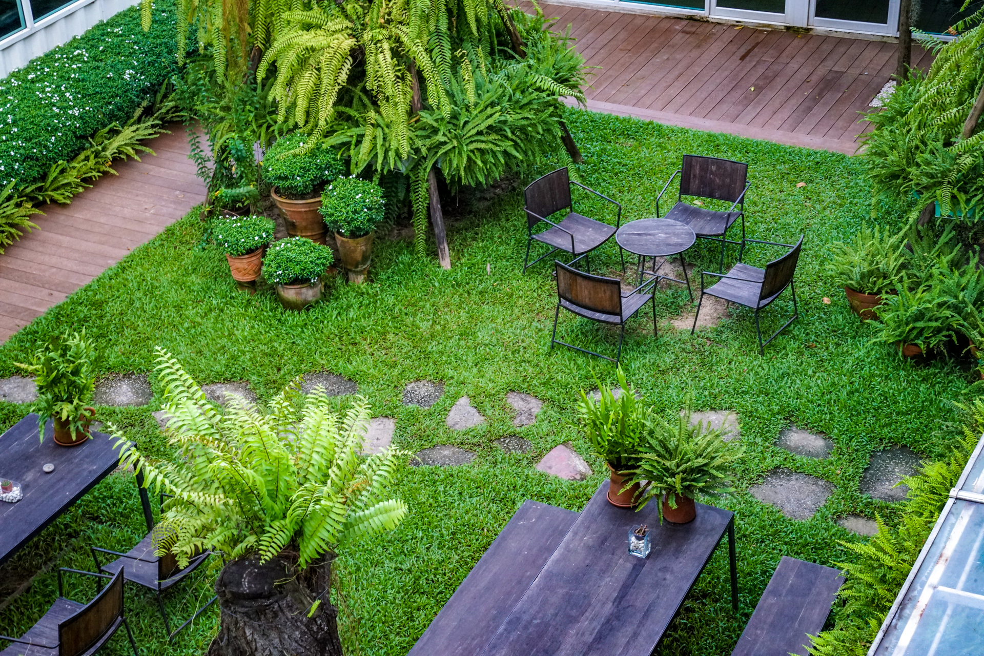 Ogród z drewnianym krzesłem i stołem. Zielone rośliny dookoła